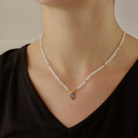 Model wearing a moonstone pendant with a gold setting and rough diamond accent.