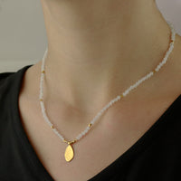 Elegant moonstone and gold hammered teardrop pendant displayed on a model, showcasing its delicate and timeless design.