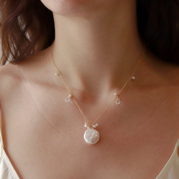 Coin pearl pendant worn on a model, showcasing the elegant design and lustrous pearl.