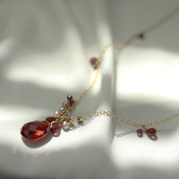 Beautiful garnet, zircon, and pearl pendant, displayed in a styled shot to highlight its elegant gemstone combination.