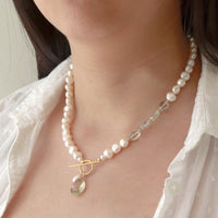 Model wearing a pearl and green amethyst toggle pendant in gold, highlighting its elegant and timeless design.