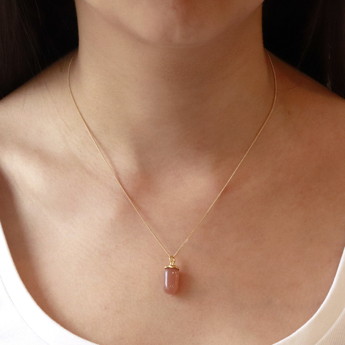 Smooth capsule pendant necklace worn on model, showcasing a sleek, minimalist design perfect for adding a modern and elegant touch to any outfit.